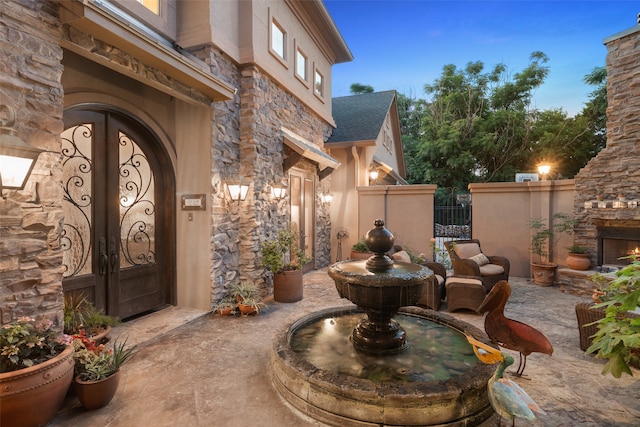 patio terrace at dusk featuring an outdoor stone fireplace