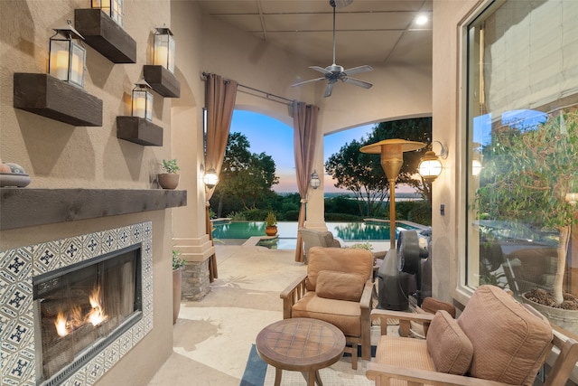 patio terrace at dusk featuring a fireplace and ceiling fan