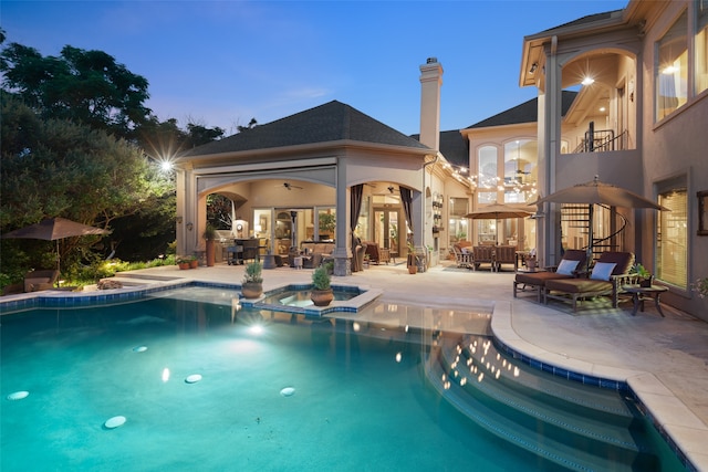 pool at dusk with a patio area and an in ground hot tub