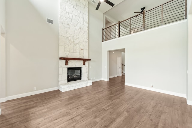 unfurnished living room featuring wood-type flooring, ceiling fan, a high ceiling, and sink