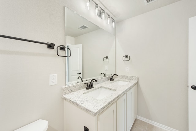 bathroom with tile flooring, toilet, vanity with extensive cabinet space, and dual sinks