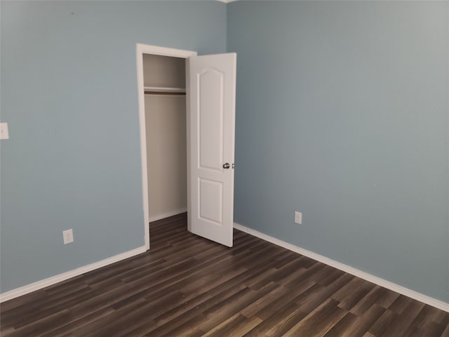 unfurnished bedroom with a closet and dark hardwood / wood-style floors