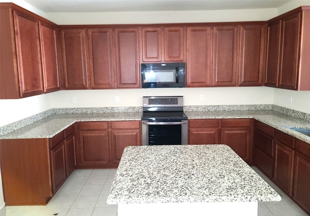 kitchen featuring stainless steel electric range oven, a kitchen island, light stone countertops, and light tile floors