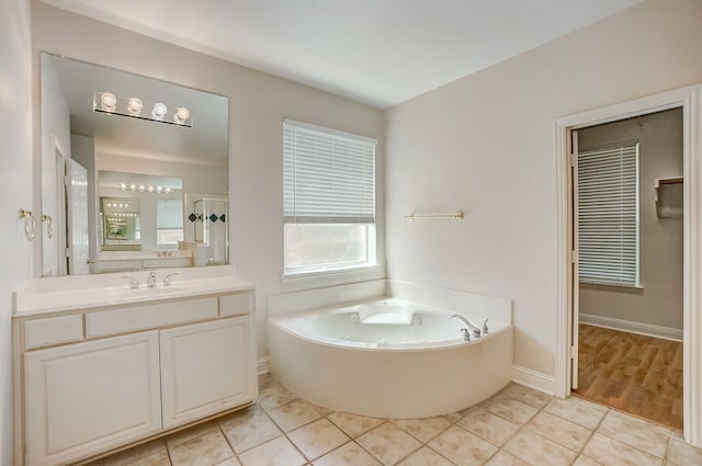 bathroom with vanity with extensive cabinet space, tile floors, and a tub