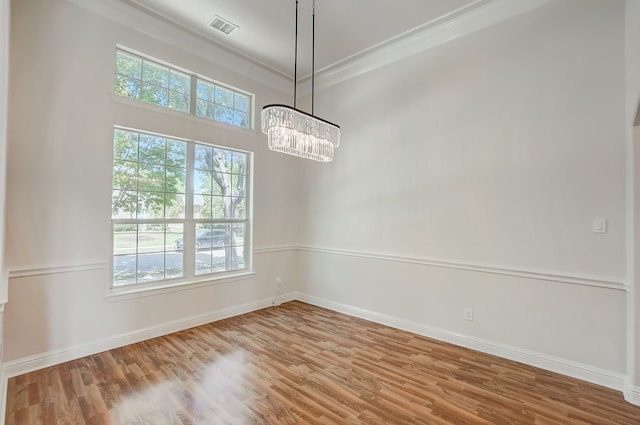 empty room featuring hardwood / wood-style floors, a healthy amount of sunlight, and a chandelier