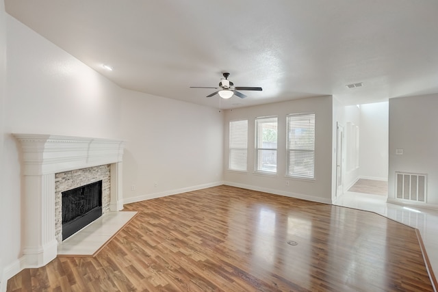 unfurnished living room featuring light wood-type flooring, ceiling fan, and a fireplace