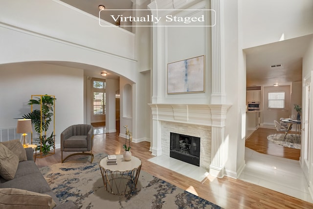 living room with a wealth of natural light, a high ceiling, hardwood / wood-style floors, and a fireplace