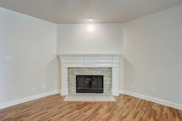 unfurnished living room with a stone fireplace and light wood-type flooring