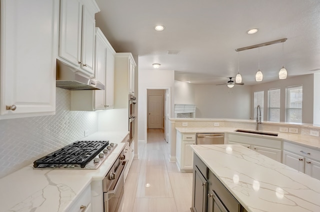 kitchen with backsplash, sink, ceiling fan, and decorative light fixtures