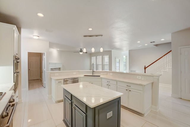 kitchen featuring a center island, hanging light fixtures, white cabinetry, sink, and light stone counters