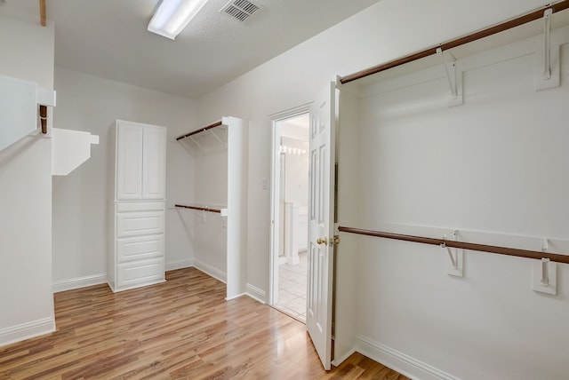 walk in closet with light hardwood / wood-style flooring