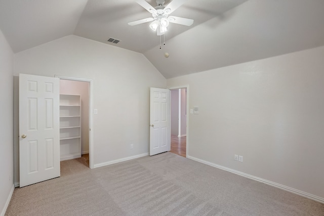 unfurnished bedroom with lofted ceiling, a walk in closet, and carpet flooring