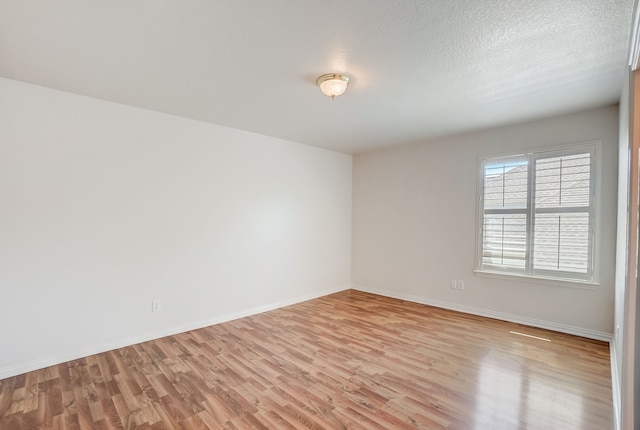 spare room with light hardwood / wood-style floors and a textured ceiling