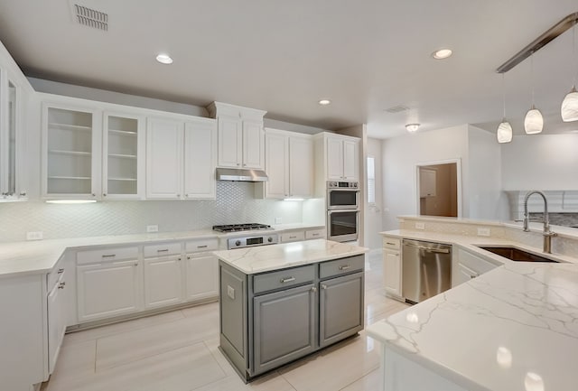 kitchen with light stone countertops, gray cabinetry, white cabinetry, backsplash, and appliances with stainless steel finishes