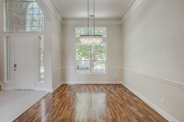 foyer entrance featuring ornamental molding, a notable chandelier, plenty of natural light, and hardwood / wood-style flooring