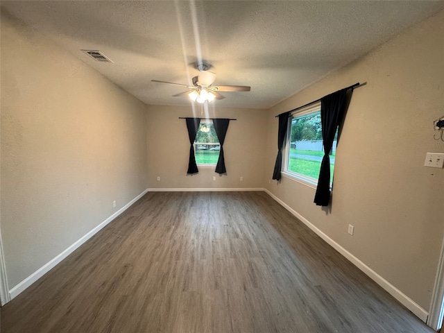 empty room featuring dark wood-type flooring, ceiling fan, and a textured ceiling