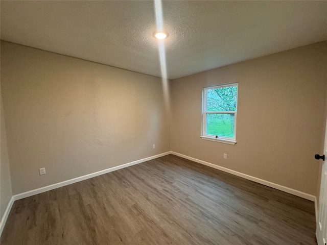 unfurnished room with dark hardwood / wood-style floors and a textured ceiling