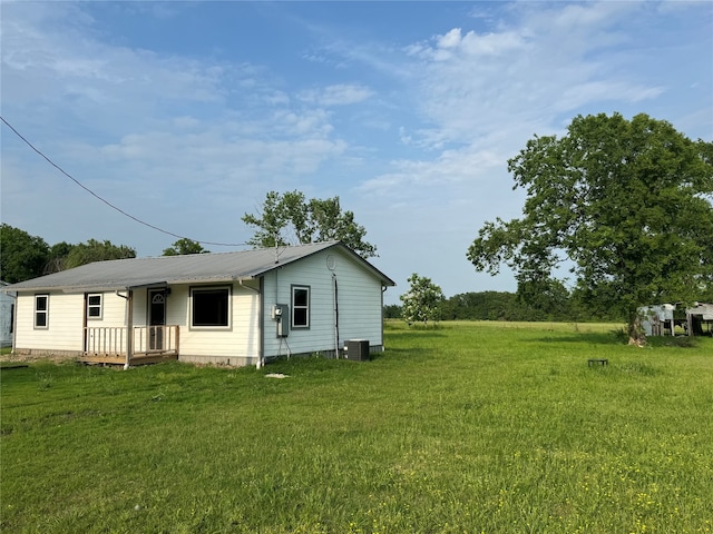 rear view of house featuring central AC unit and a lawn