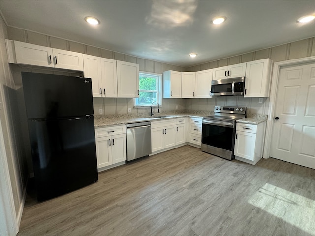 kitchen with light hardwood / wood-style floors, stainless steel appliances, white cabinetry, and sink