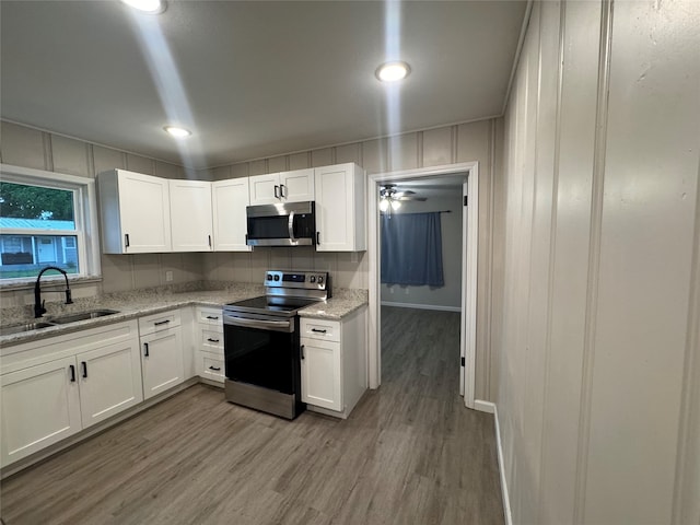 kitchen with white cabinets, sink, appliances with stainless steel finishes, and hardwood / wood-style flooring