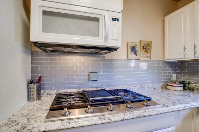 kitchen featuring tasteful backsplash, stainless steel gas cooktop, white cabinetry, and light stone countertops