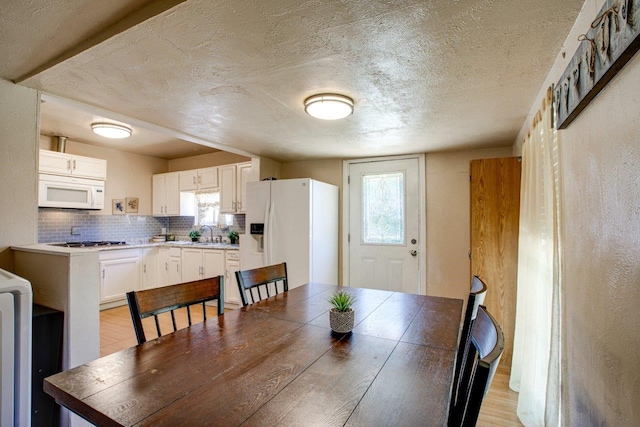 dining space with sink, light hardwood / wood-style flooring, and a textured ceiling