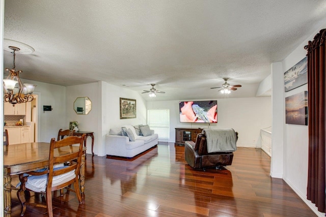 living room with ceiling fan with notable chandelier, a textured ceiling, and dark wood-type flooring