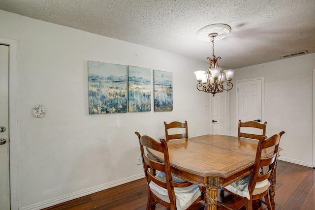 dining space with a textured ceiling, dark hardwood / wood-style flooring, and an inviting chandelier