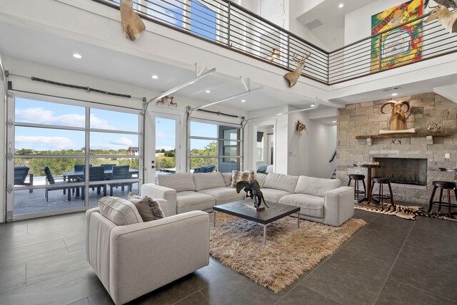 living room featuring a towering ceiling, a fireplace, and dark tile patterned flooring