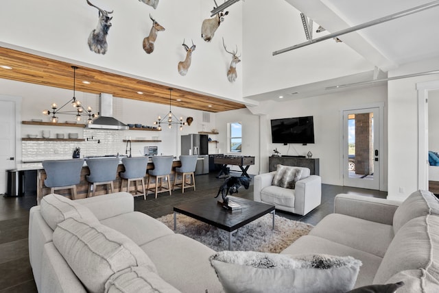 living room with an inviting chandelier, beam ceiling, and a healthy amount of sunlight