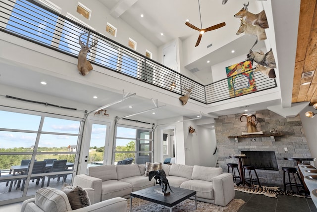 living room with dark tile patterned floors, a fireplace, ceiling fan, and a high ceiling