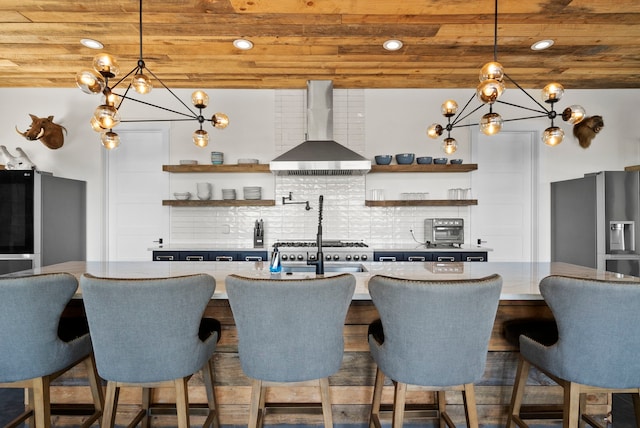 bar with pendant lighting, wall chimney range hood, decorative backsplash, and stainless steel fridge with ice dispenser