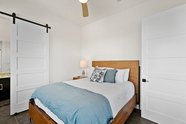 tiled bedroom featuring a barn door and ceiling fan