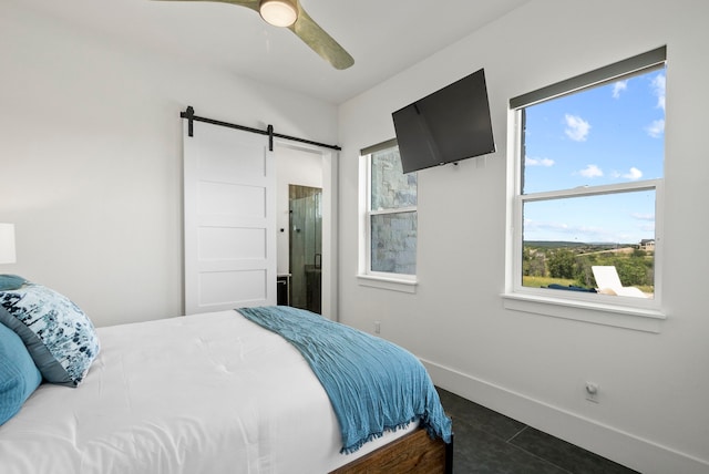 bedroom featuring ceiling fan, a barn door, and dark tile patterned flooring