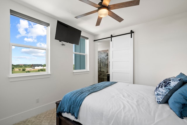 bedroom featuring ceiling fan, ensuite bathroom, a barn door, and multiple windows