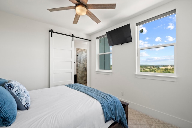 bedroom featuring ensuite bath, a barn door, and ceiling fan