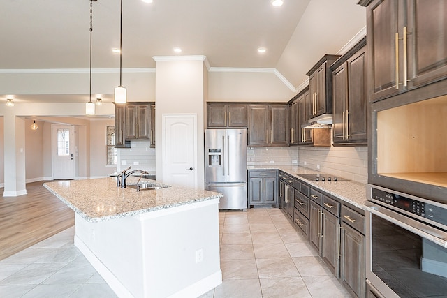 kitchen featuring pendant lighting, backsplash, stainless steel appliances, vaulted ceiling, and a center island with sink