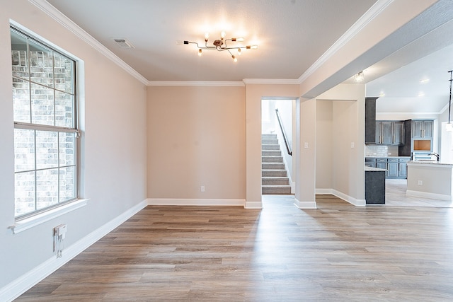 unfurnished room featuring ornamental molding, light hardwood / wood-style flooring, and a chandelier