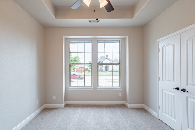 carpeted spare room featuring ceiling fan and a tray ceiling