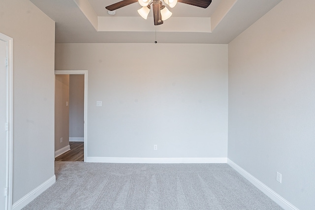 unfurnished room featuring ceiling fan, a tray ceiling, and carpet flooring