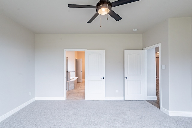 unfurnished bedroom with light colored carpet, ensuite bath, and ceiling fan