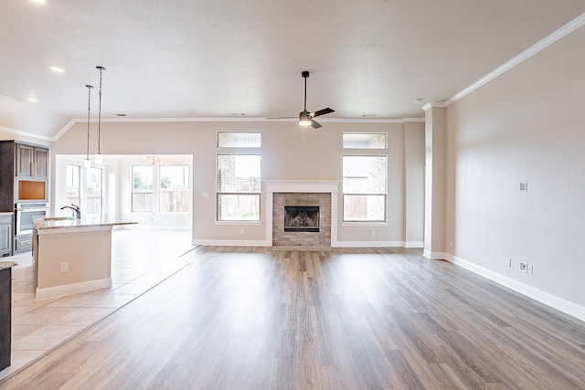 unfurnished living room featuring ornamental molding, ceiling fan, lofted ceiling, and light tile flooring