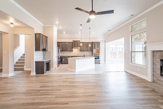 interior space with a brick fireplace, ceiling fan, sink, light wood-type flooring, and ornamental molding