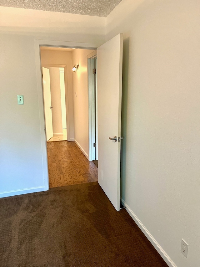 hall featuring a textured ceiling and dark hardwood / wood-style floors