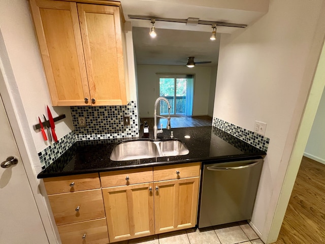 kitchen featuring rail lighting, light hardwood / wood-style flooring, dishwasher, dark stone countertops, and sink