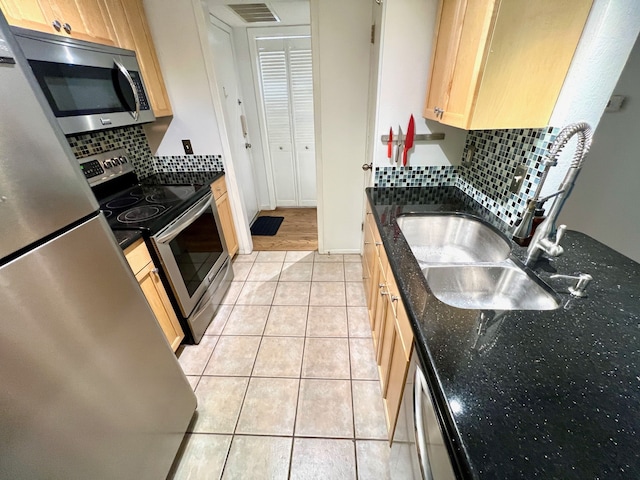 kitchen featuring tasteful backsplash, light tile patterned floors, dark stone counters, sink, and stainless steel appliances