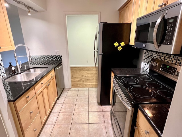 kitchen featuring track lighting, sink, backsplash, stainless steel appliances, and light tile patterned floors