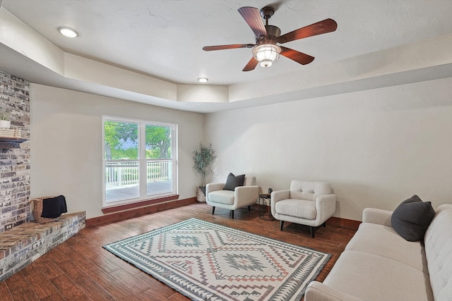 living room featuring dark hardwood / wood-style floors, a fireplace, brick wall, and ceiling fan