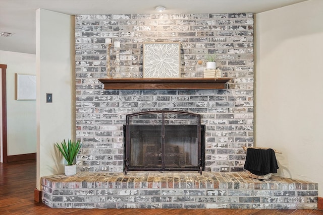 interior details with wood-type flooring and a brick fireplace