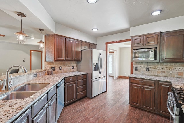 kitchen with tasteful backsplash, stainless steel appliances, sink, decorative light fixtures, and dark hardwood / wood-style floors